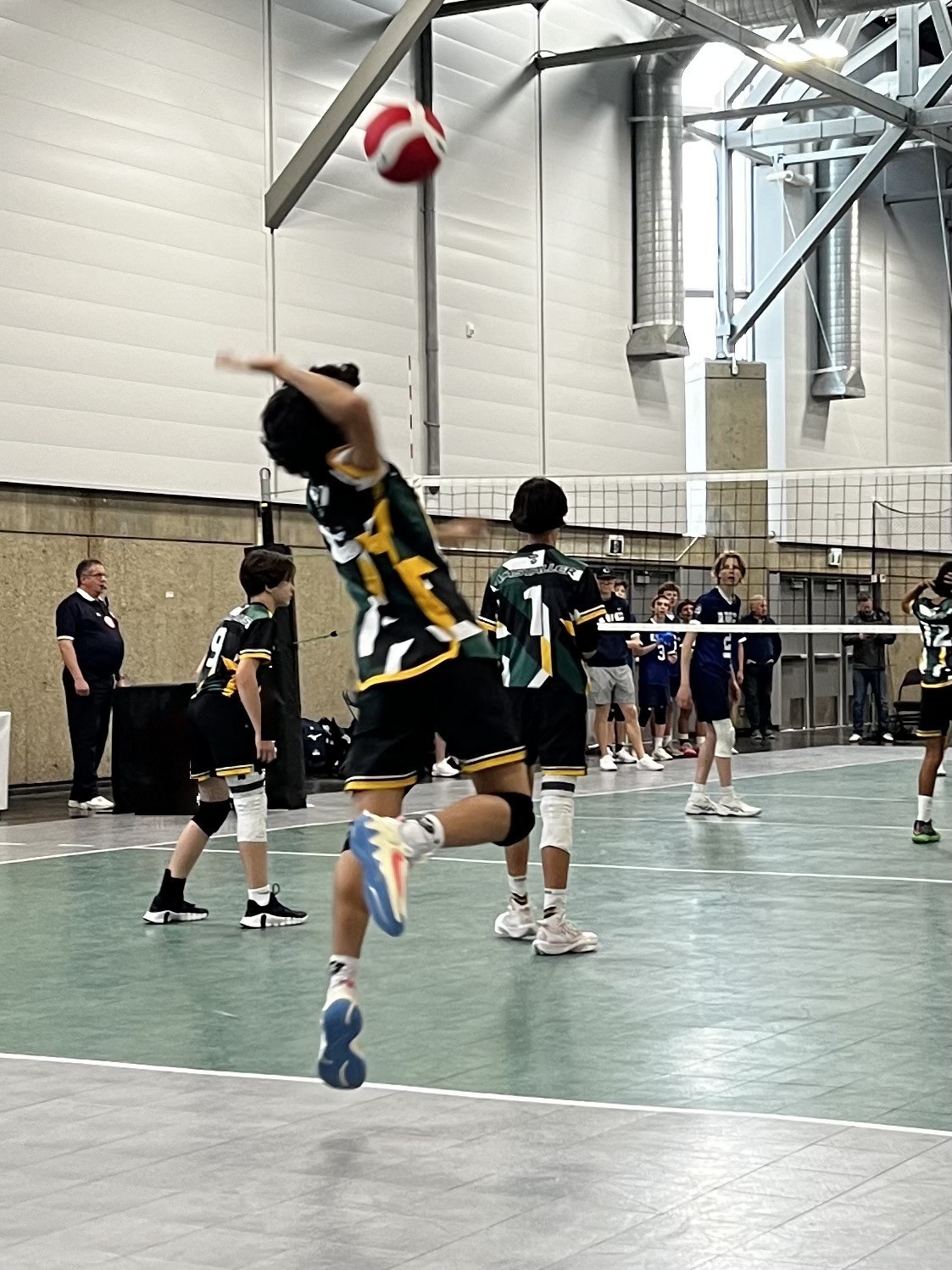 Volleyball player leaping into a jump serve, ball in the air above him